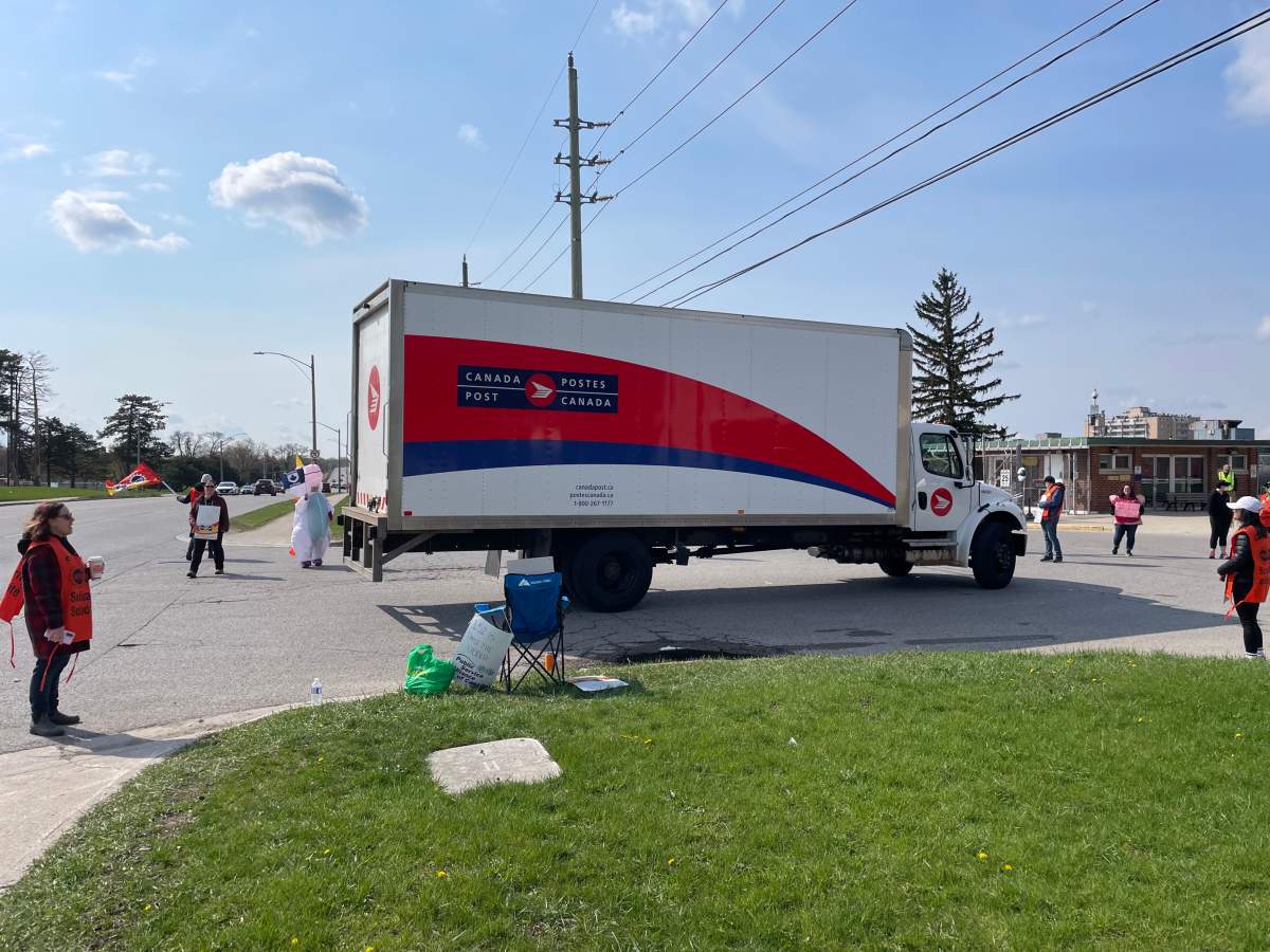 A Canada Post vehicle surrounded by striking PSAC workers in London, Ont., on April 25, 2023.