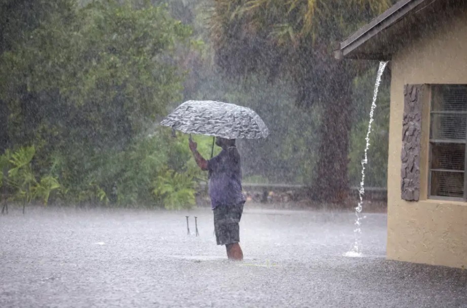 A man stops to take pictures of his flooded neighborhood along SW 3rd Street and SW 4th Ave in Dania Beach, Fla., on Wednesday, April 12, 2023.