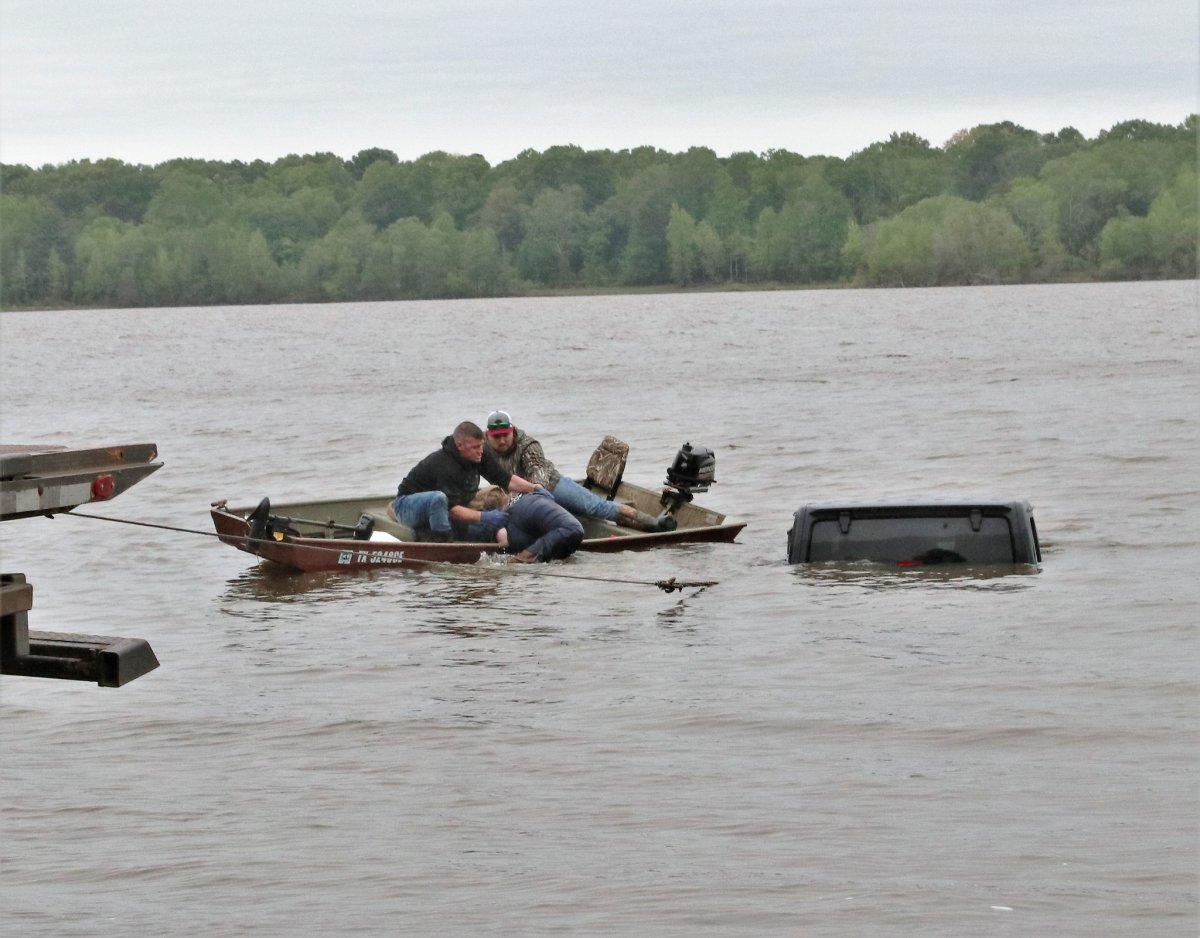 A fisherman and tow-truck worker pull a woman from a submerged Jeep from a lake in east Texas on April 7, 2023.