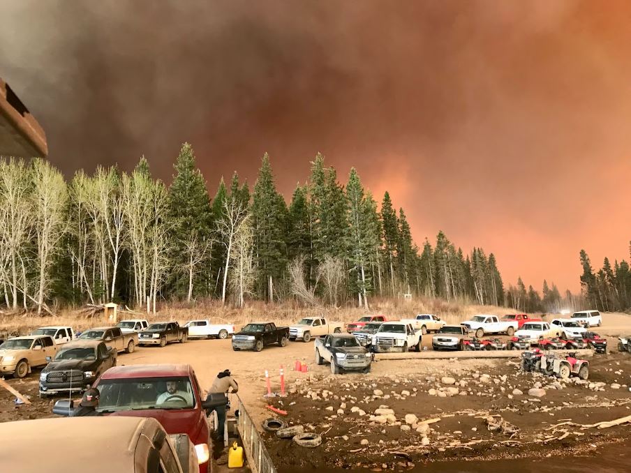 Dozens of vehicles on the shore of the Peace River as a wildfire threatens the remote community of Fox Lake.