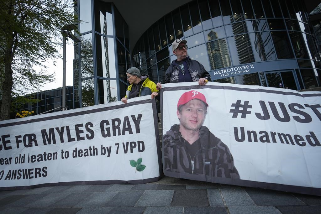 Protesters hold banners with a photograph of Myles Gray, who died following a confrontation with several police officers in 2015, before the start of a coroner's inquest into his death, in Burnaby, B.C., on Monday, April 17, 2023.