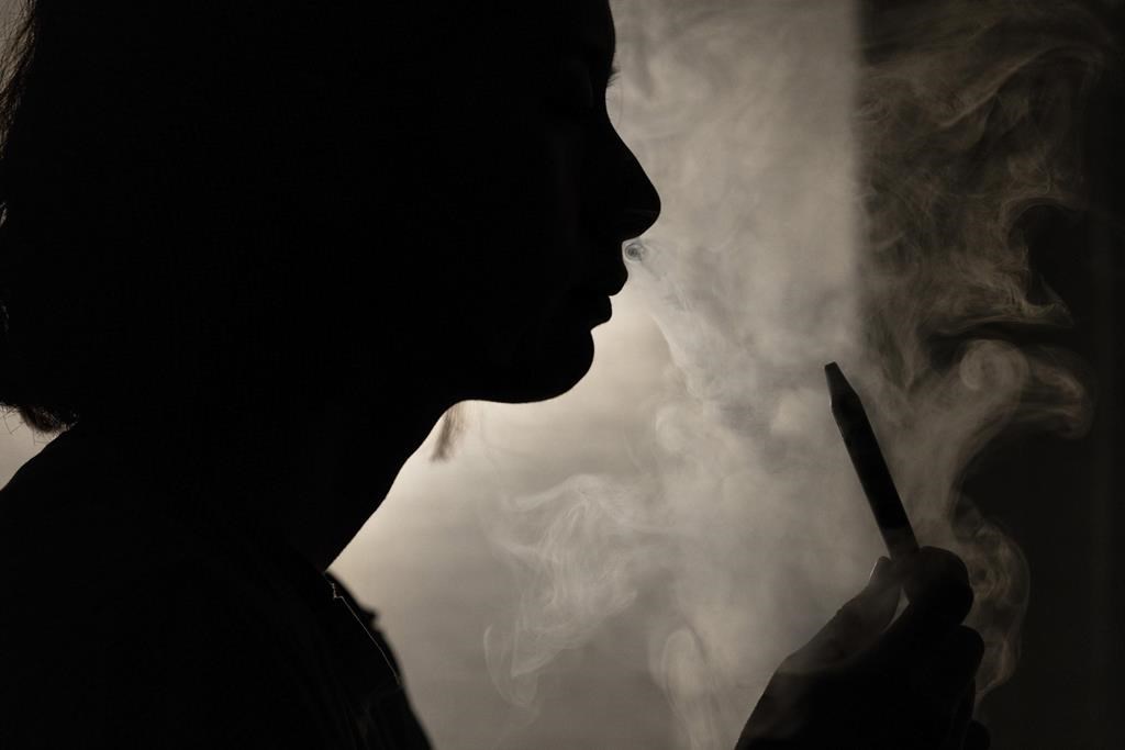 A person poses for a photograph as they vape in Melbourne, March 23, 2023.