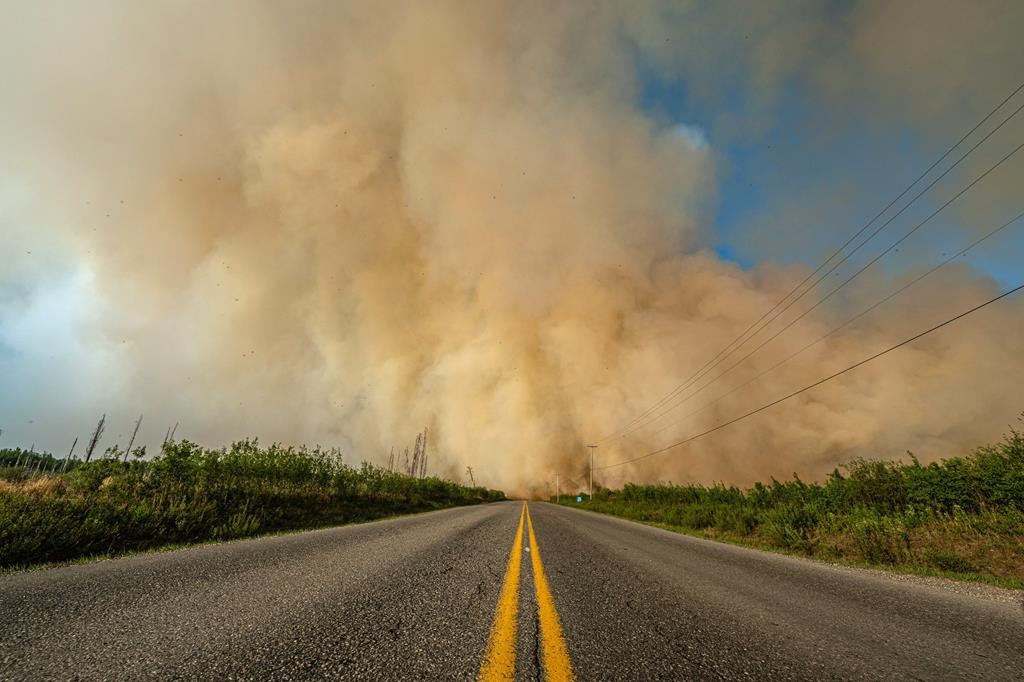 Smoke from a wildfire is shown crossing a road in British Columbia in this undated handout image provided by the BC Wildfire Service.