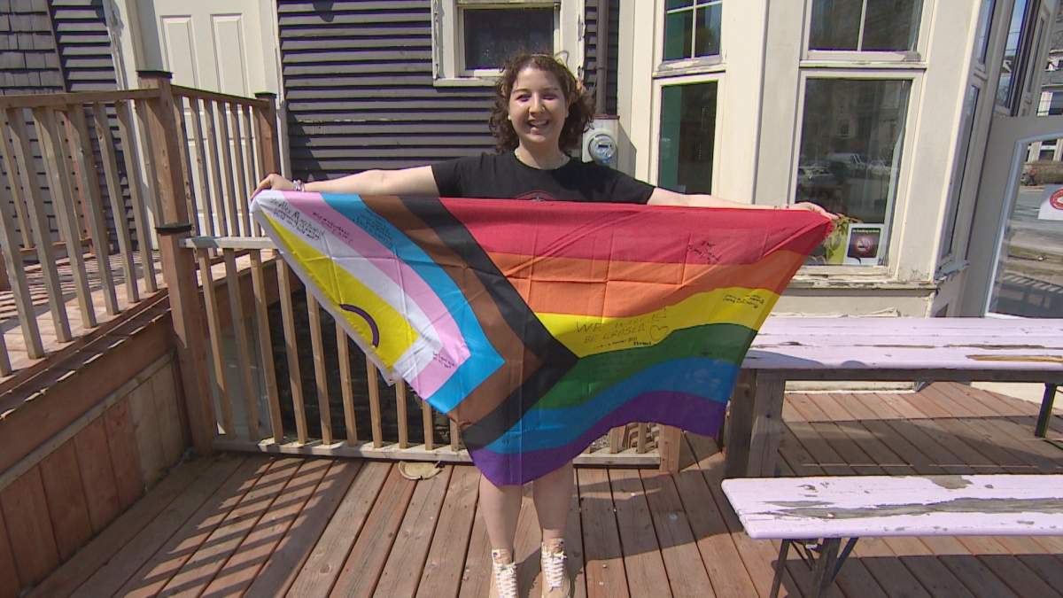 Alex Marchand holds up a Pride flag, which is available Monday for community members to sign. The flag will be donated to Bay View High School, where a Pride flag was burned last month.