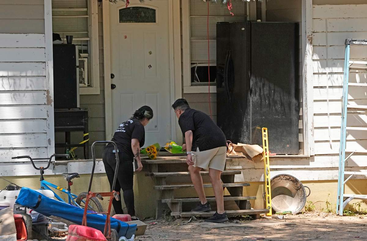 Melissa Salcido, left, and Isaiah Alvarado place flowers on the porch, Sunday, April 30, 2023, at the scene where a mass shooting occurred Friday night, in Cleveland, Texas. The search for a Texas man who allegedly shot his neighbors after they asked him to stop firing off rounds in his yard stretched into a second day Sunday, with authorities saying the man could be anywhere by now. (AP Photo/David J. Phillip)
