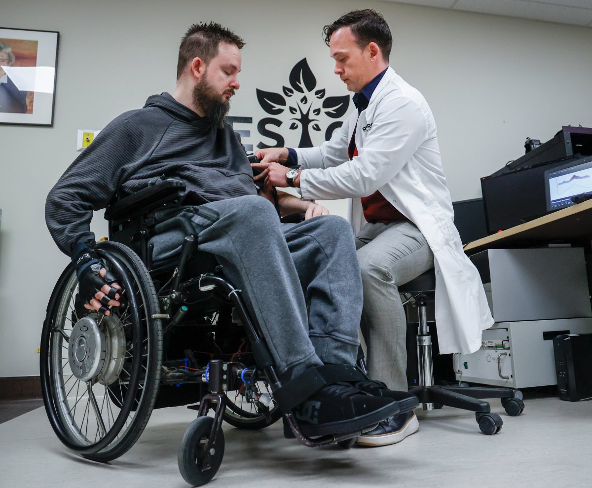 Dr. Aaron Phillips, right, takes the blood pressure of study participant Nick Wiltshire as researchers at the University of Calgary are developing new technologies for people living with neurological disorders, in Calgary, Alta., Friday, April 28, 2023.