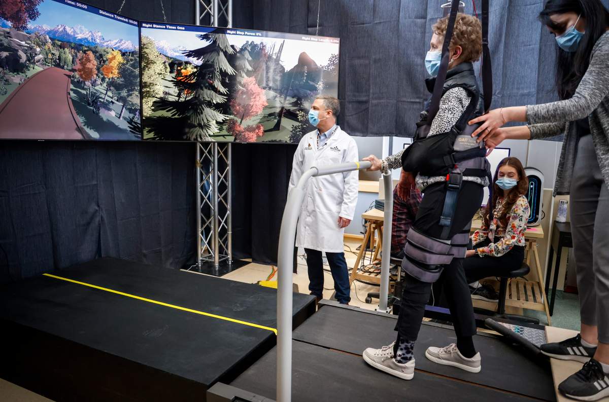 Dr. Sean Dukelow, left, looks on as Judy Kirton, centre, walks on a treadmill with the help of physiotherapist Tanya Chopra, as researchers at the University of Calgary work to develop new technologies for people living with neurological disorders, in Calgary, Alta., Friday, April 28, 2023.