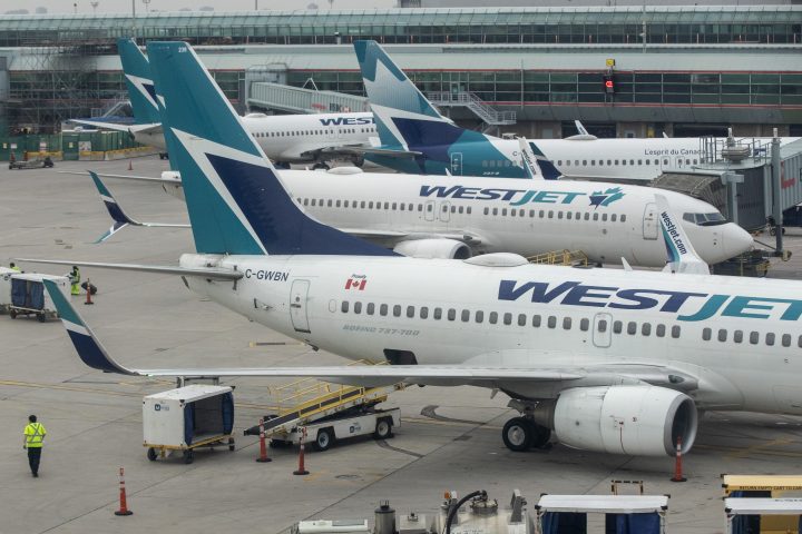 An airport employee walks beside a WestJet plane on the tarmac at Toronto Pearson International airport in Toronto, Ontario on Friday March 18, 2022. 