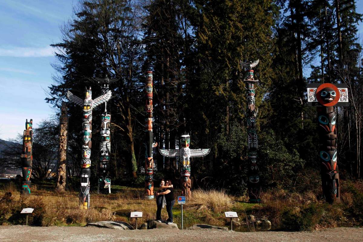 Nine totem poles stand amid a park