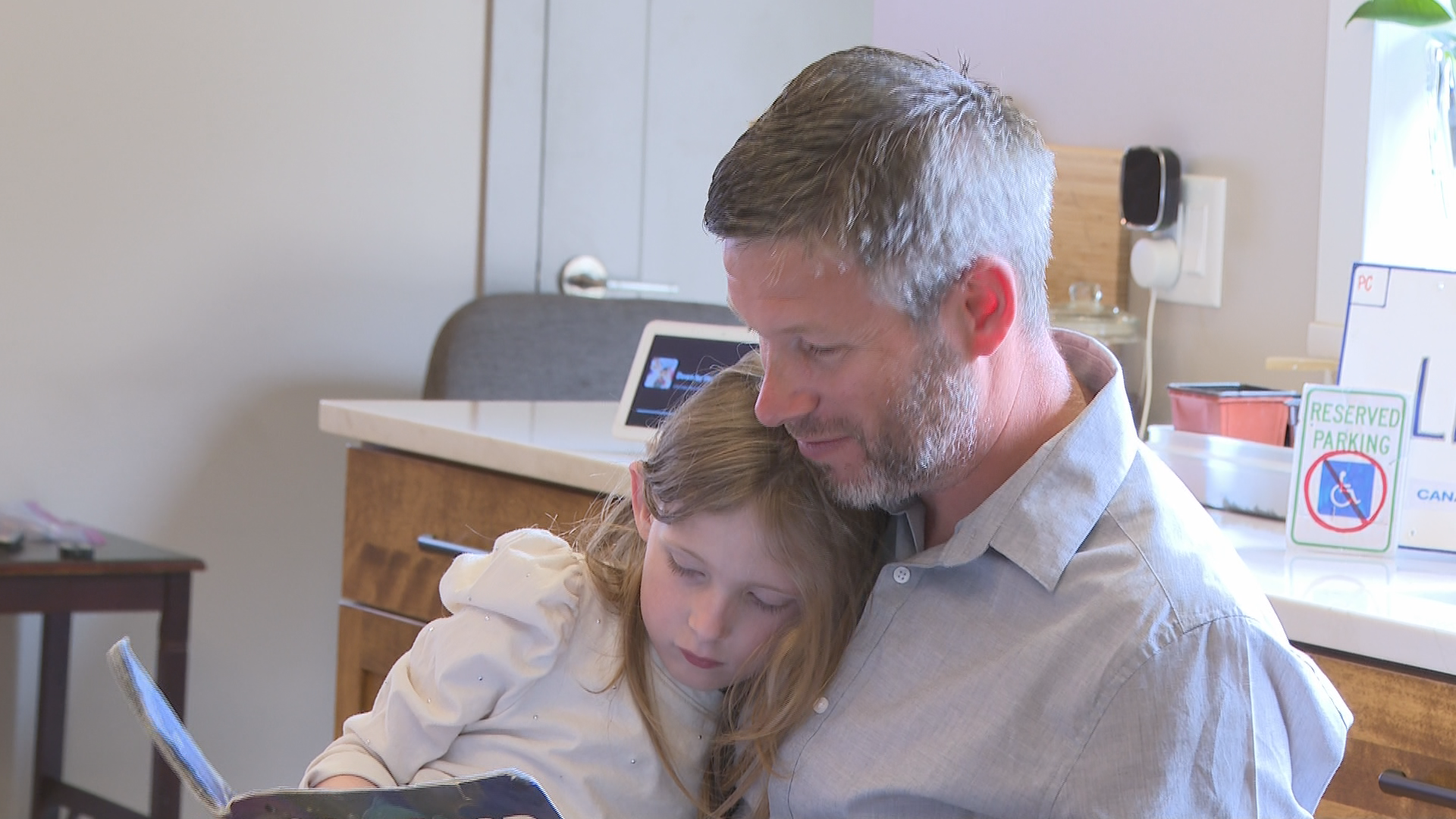 Emerson Robichaud-King, 7, reads a book with her dad, Dale King.