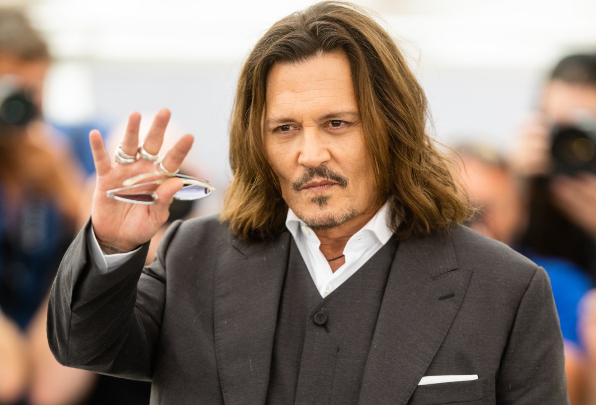 Johnny Depp in a black suit. He is holding a pair of sunglasses.