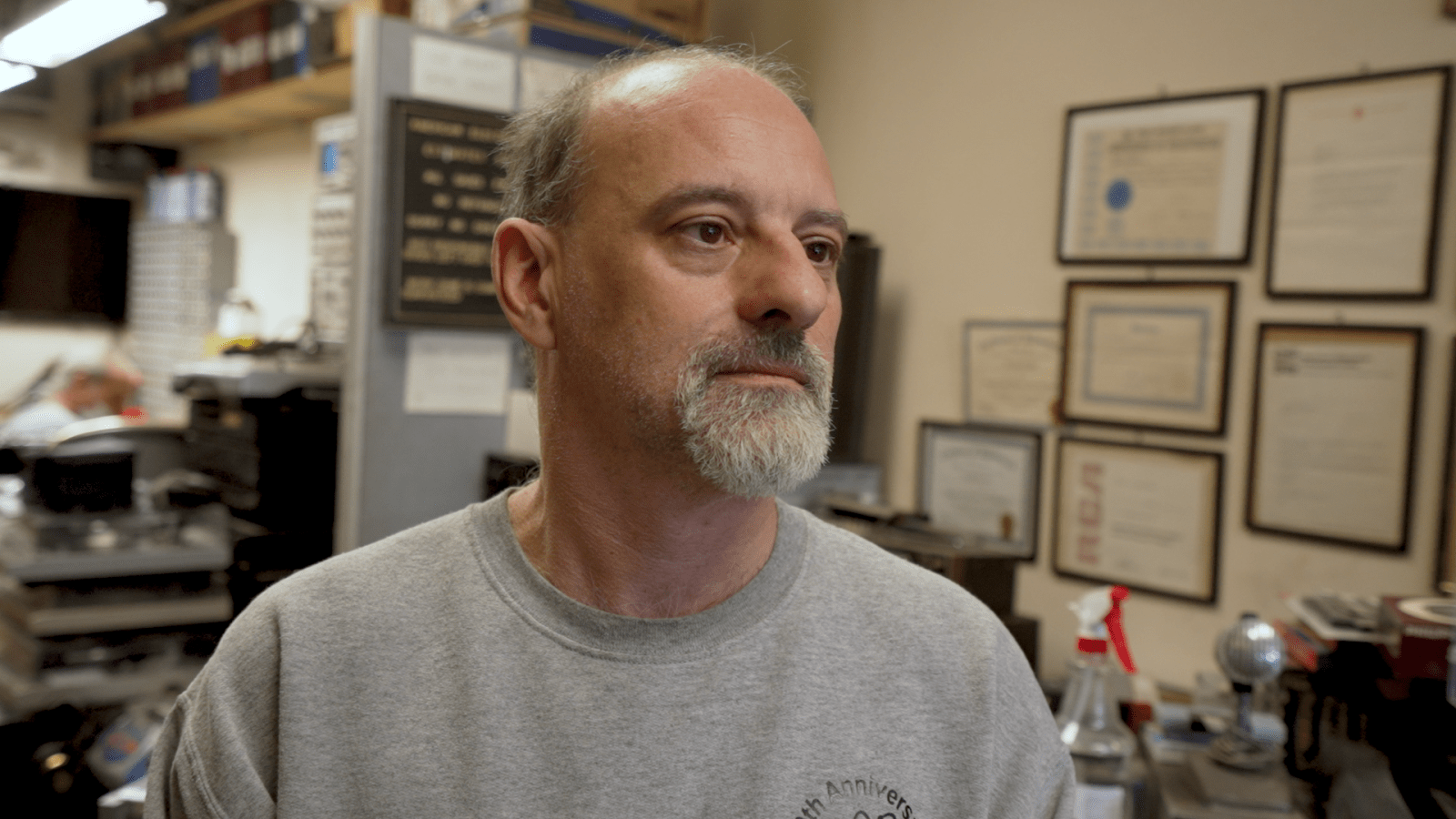 John Fadel at American Electronics. On the wall behind him is his electrical engineering degree and various other certificates.