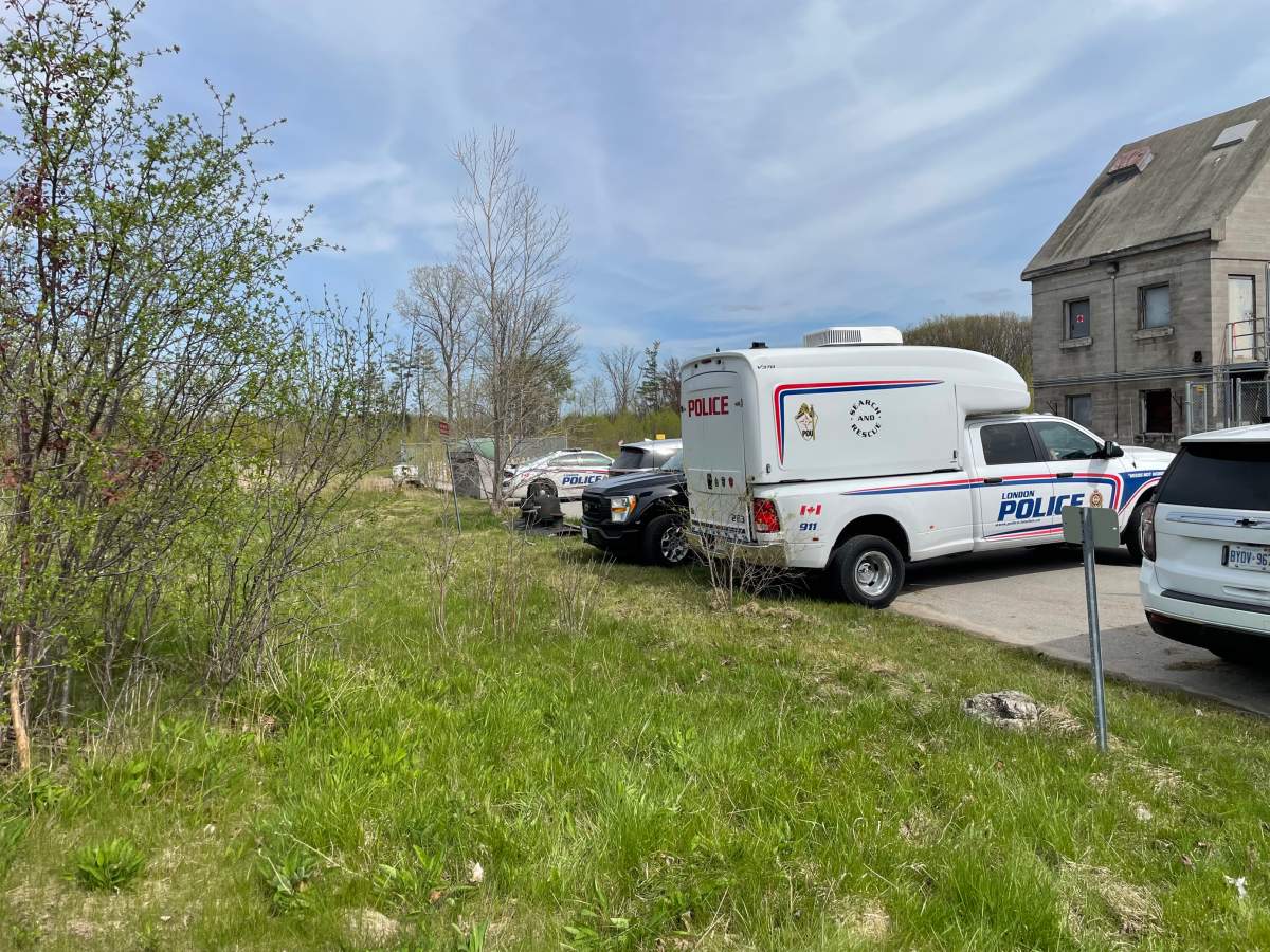 Police vehicles in a parking lot off of a wooded area on a sunny day.