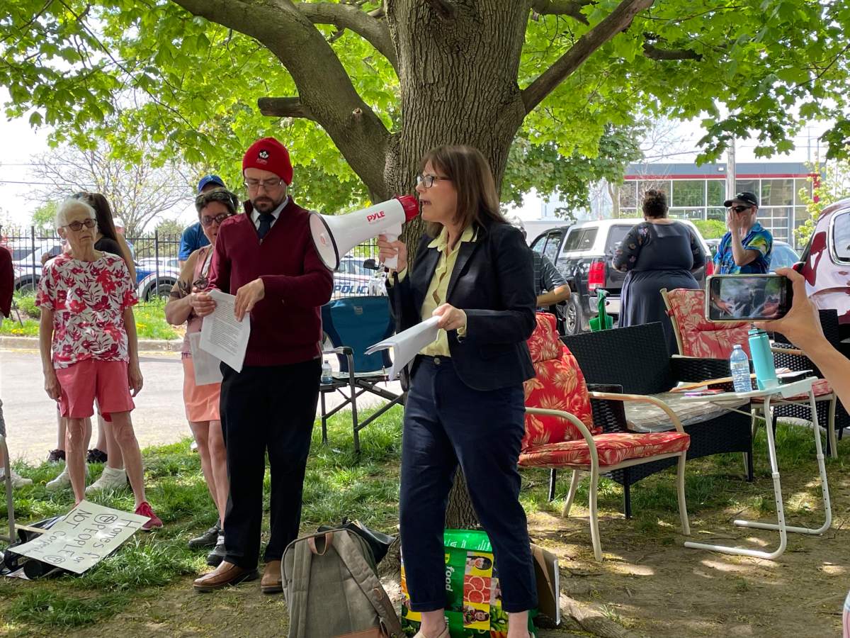 MPP Teresa Armstrong speaks into a megaphone to the right of Jordan Smith, with ACORN.