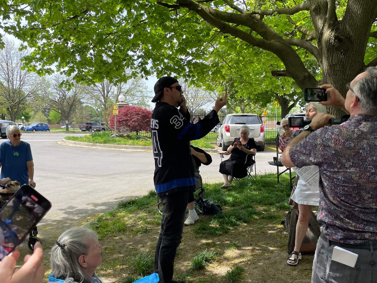 A man in a Toronto Maple Leafs Jersey gets into a verbal altercation with others on a sunny day under a tree in London, Ont.