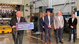Premier Doug Ford stands at a podium while other politicians stand to his right at a manufacturing facility in London, Ont., on May 24, 2023.
