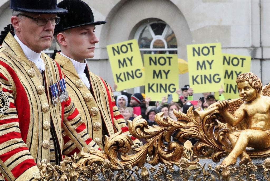TOPSHOT - A coach carrying Britain's Prince William, Catherine, Princess of Wales and their children Prince George, Princess Charlotte and Prince Louis rides past anti-monarchy protesters following the coronation ceremony for Britain's King Charles III and Queen Camilla.