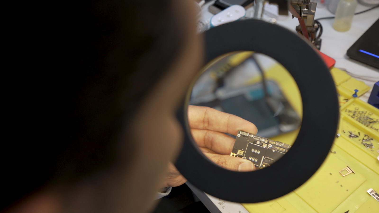Technician Rayhan Mohammed Siraj examines a motherboard of a cellphone with his magnifying glass. Siraj is the owner of Phone Solutions, an independent cellphone repair shop in Toronto.