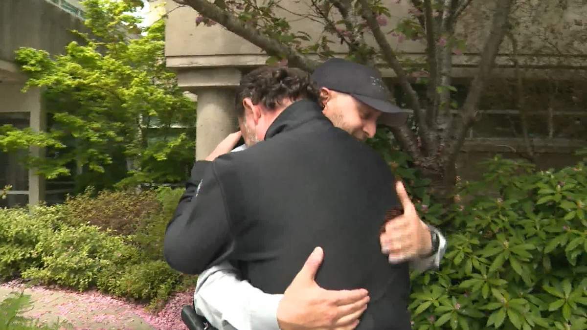 Burnaby Fire Capt. Paul Rushton embraces Surrey RCMP Const. Steve Dalton on May 8, 2023, one day after the pair dove into the icy Nicomekl River in Surrey, B.C. to rescue stranded motorists.