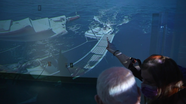 Staff and a patient with dementia looking at a sailboat in water in the 360 virtual room