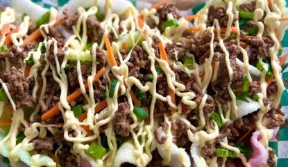 Piles of crunchy shrimp chips layered with Asian-style beef crumbles, carrot, green onions and finished with a drizzle of sweet mayo.