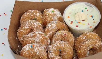 One dozen vanilla cookie mini donuts served with a dunk-able rainbow chip frosting.