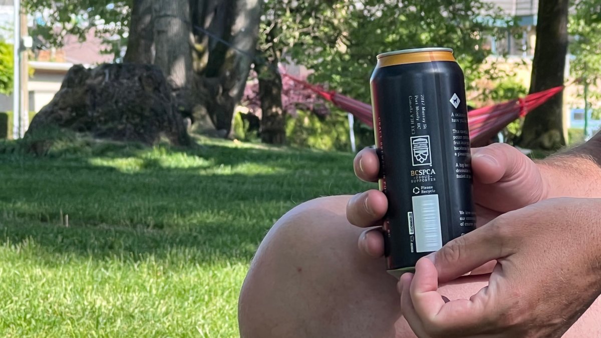 Hands holding a can of beer in a Vancouver park.