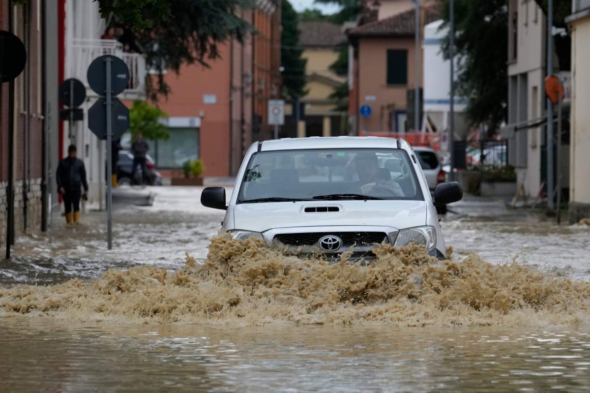 A car crosses a street in the flooded village of Castel Bolognese, Italy, Wednesday, May 17, 2023.