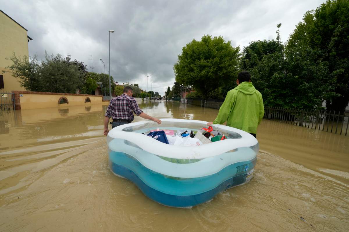 Residents use a plastic portable pool to remove personal belongings, on a flooded road of Lugo, Italy, Thursday, May 18, 2023.