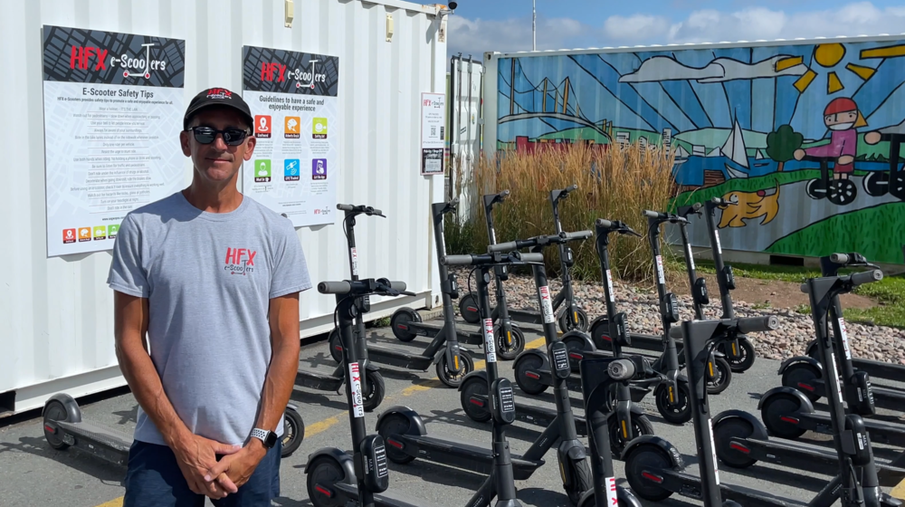 Max Rastelli stands in front of a batch of his e-scooters.
