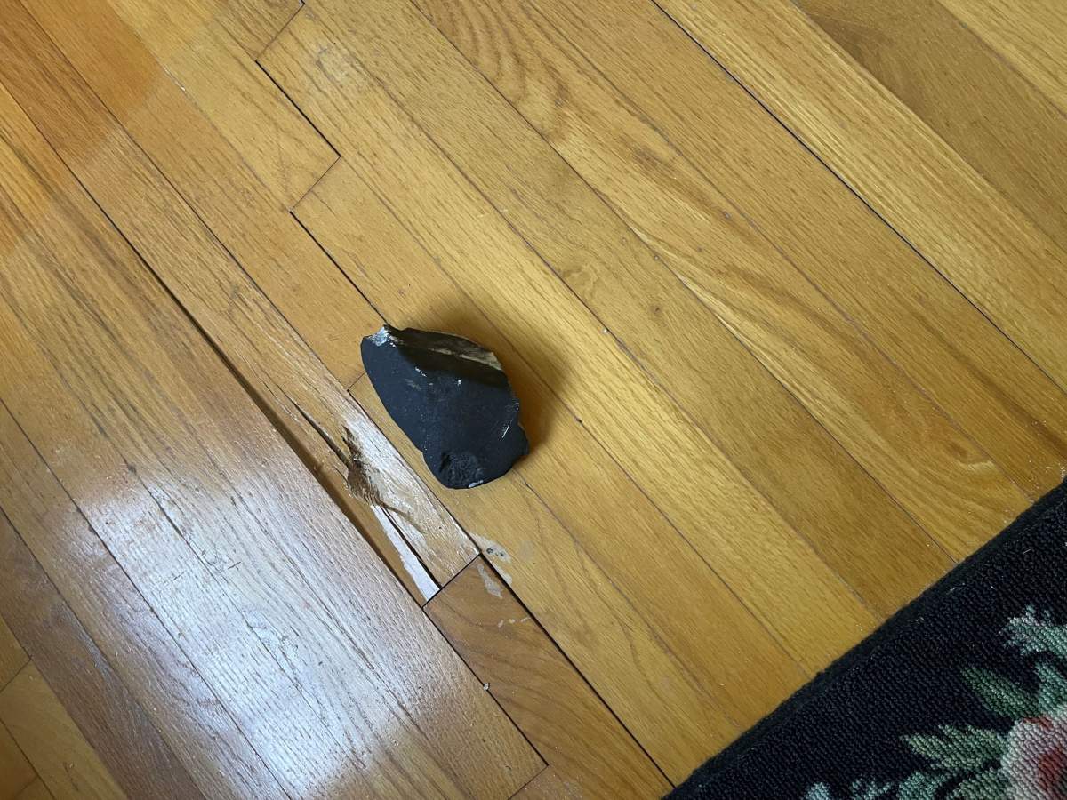 The meteorite on the hardwood floor next to a dent.