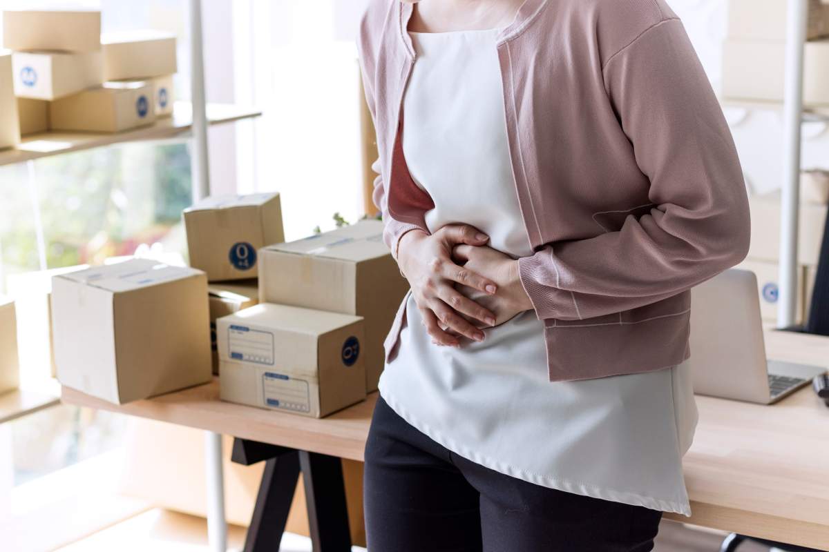 A woman suffering from menstruation pain during work in the office.