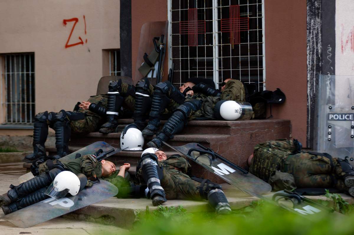 Polish soldiers, part of the peacekeeping mission in Kosovo KFOR, rest in front of a municipal building in the town of Zvecan, northern Kosovo, on Tuesday.  (AP Photo/Marjan Vucetic)