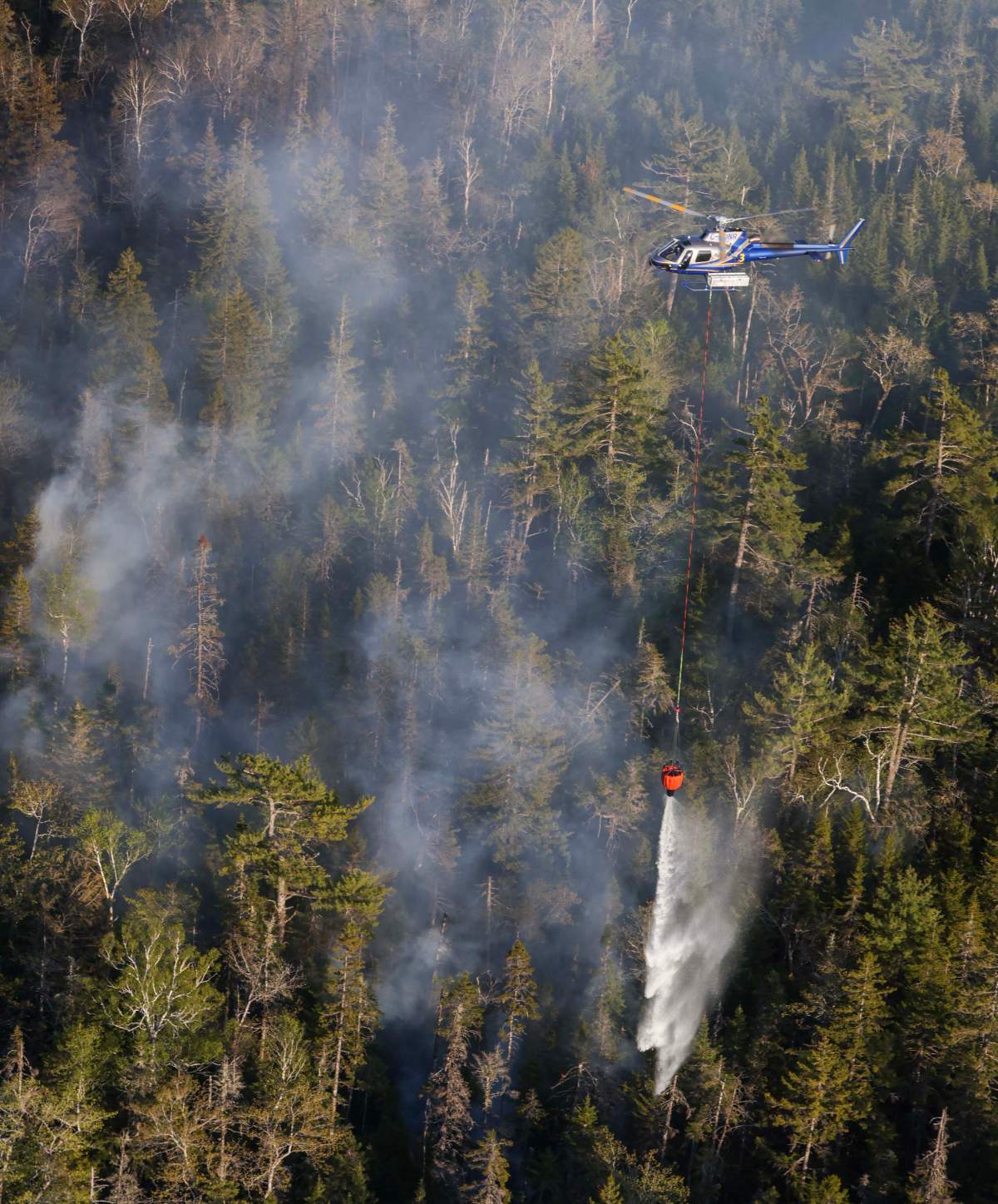 A helicopter drops water on the wildfire in Tantallon.