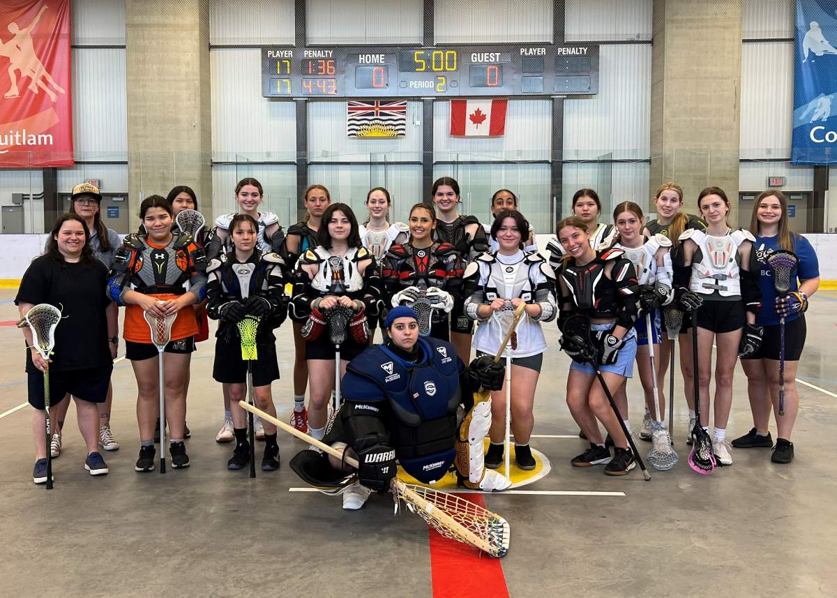 A group of lacrosse players pose for a picture inside of a stadium.