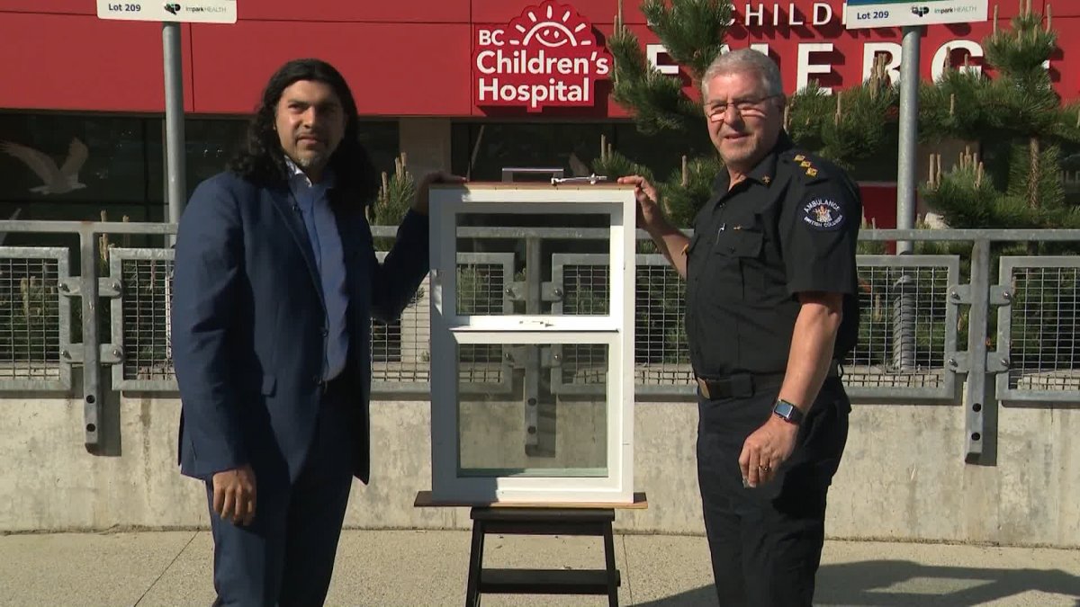 BC Children's Hospital pediatric neurosurgeon Dr. Faizal Haji (left) demonstrates use of a window lock with paramedic Brian Twaites during an annual children's fall prevention campaign in Vancouver on Mon. May 15, 2023.
