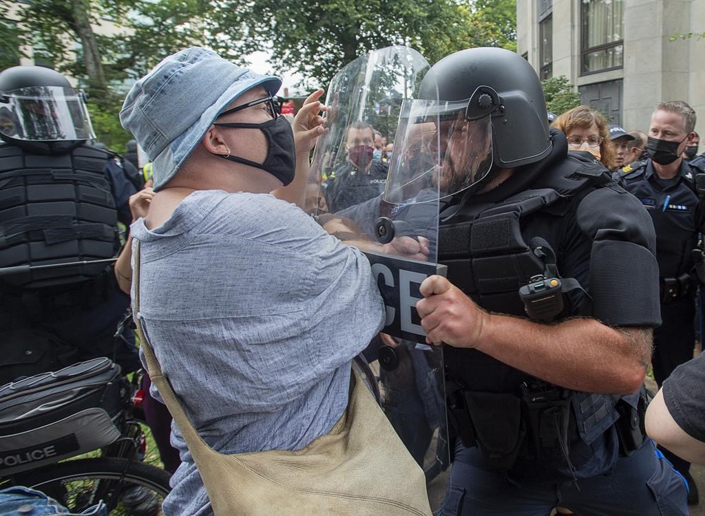 Protesters jostle with police at a protest after the city removed tents and small shelters for homeless people in Halifax on Wednesday, Aug. 18, 2021. A judge has acquitted a man accused of throwing a bottle at police during a Halifax housing protest in one of the first decisions in a series of trials related to the 2021 demonstration. THE CANADIAN PRESS/Andrew Vaughan.