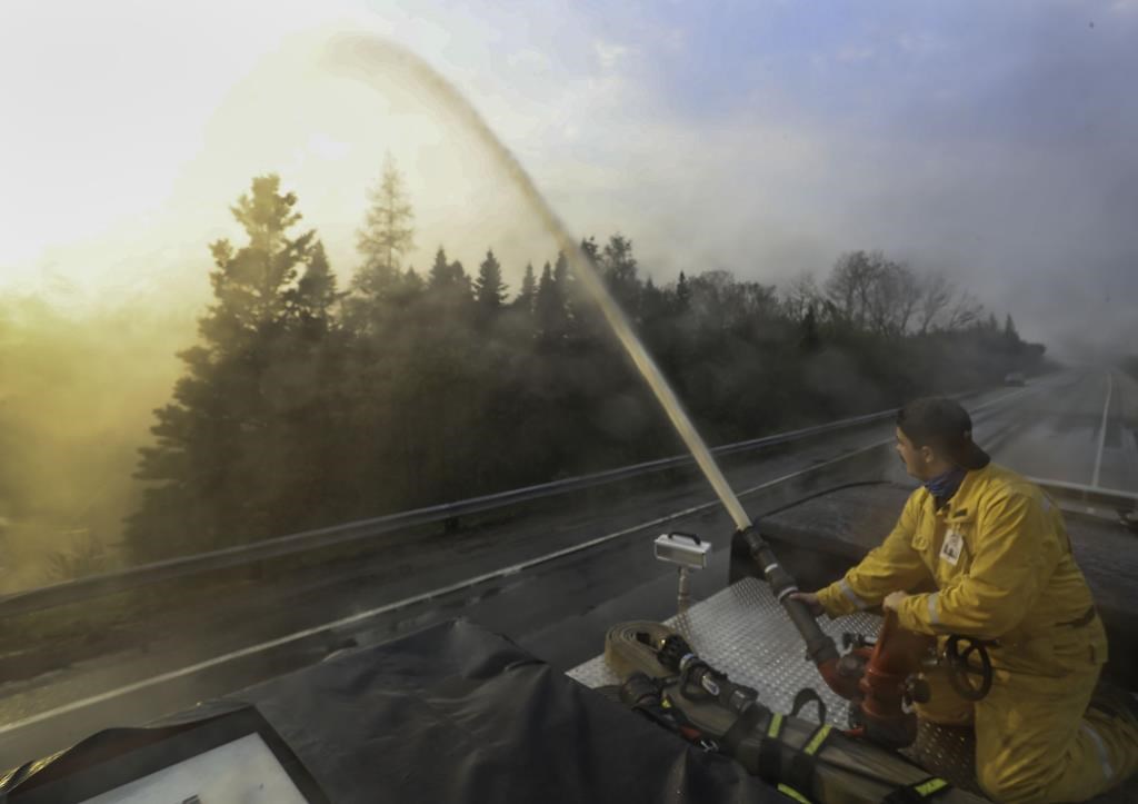 Northfield fire department member Seth Slauenwhite sprays down a flare up along Highway 103, near Shelburne, N.S., in this Saturday, June 3, 2023, handout photo.