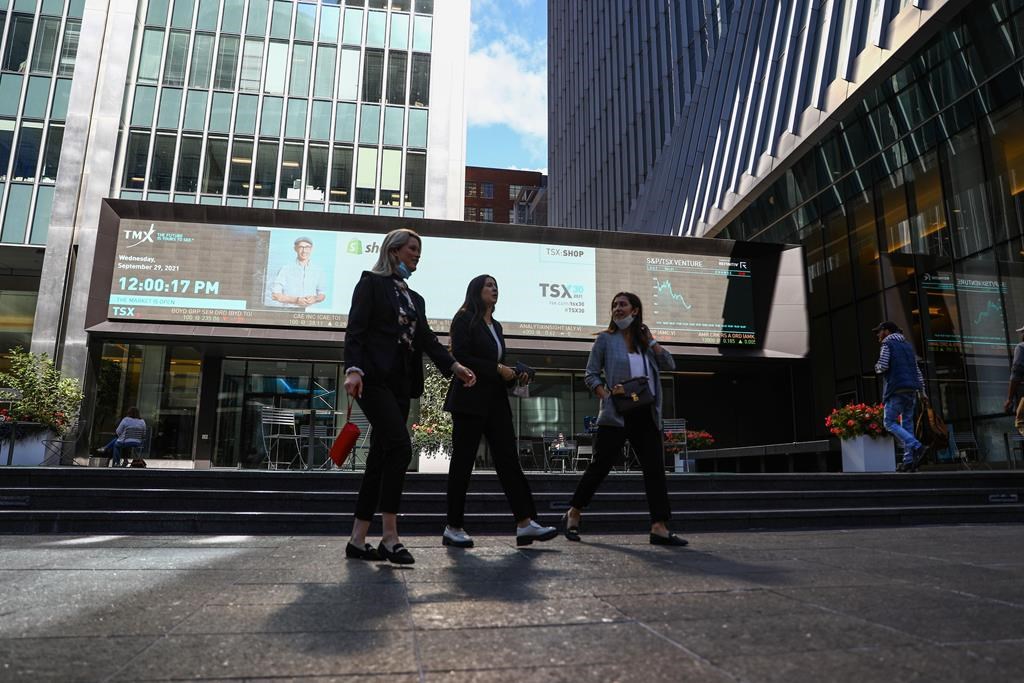 A sign board displays the TSX level as women walk past the Richmond-Adelaide Centre in the financial district in Toronto on Wednesday, September 29, 2021. THE CANADIAN PRESS/Evan Buhler.