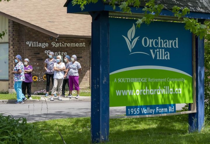 Workers watch as nursing union members show their support at the Orchard Villa Long-Term Care in Pickering, Ont. on Monday June 1, 2020. Ontario has used its powers to push through the redevelopment of three long-term care homes run by a company that was devastated by deaths during the pandemic.