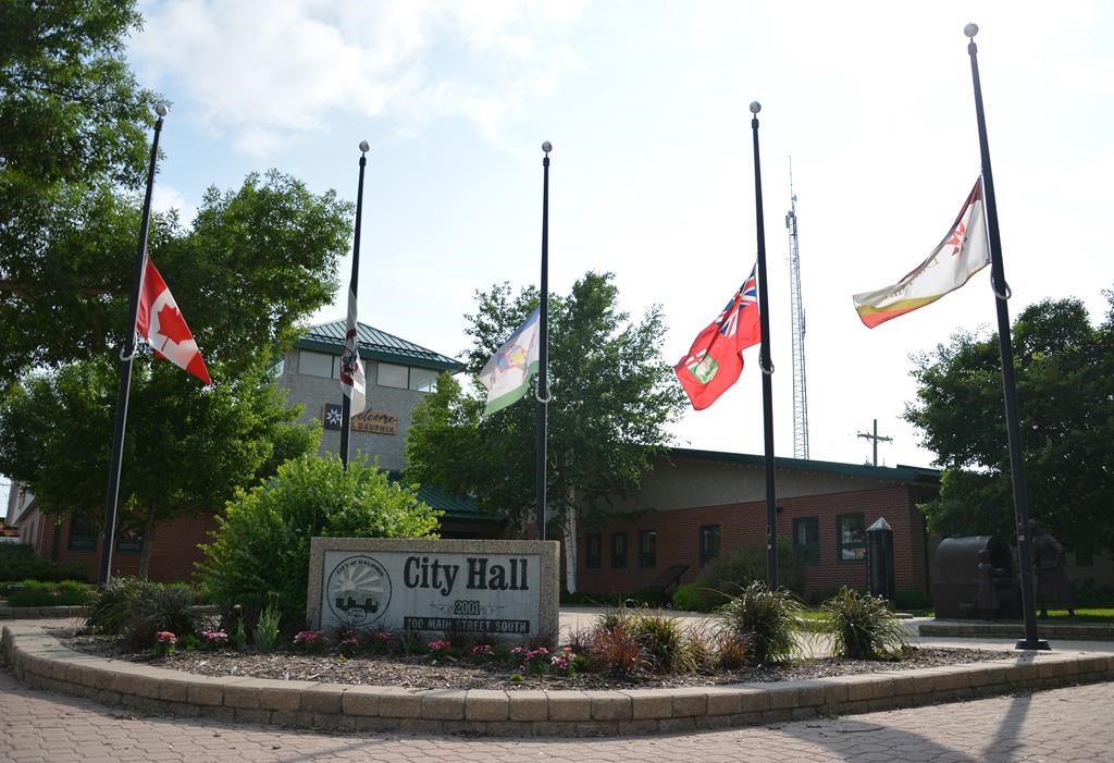 Flags outside Dauphin city hall fly at half mast on Friday. A western Manitoba community is grappling with how to honour the lives lost in a fiery bus crash that killed 15 seniors last week.
