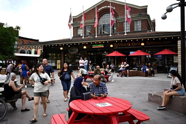 People walk over flowers painted onto the pavement along a section of William Street that is closed to vehicular traffic in the ByWard Market in Ottawa, on Friday, June 23, 2023. 