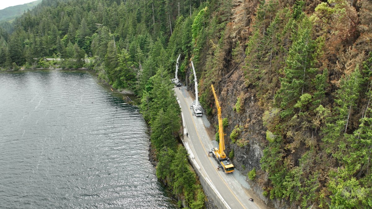 Cranes are seen during the installation of new safety equipment on a portion of Highway 4 near Port Alberni, B.C. on June 19, 2023. The stability of the slope was compromised by the nearby Cameron Bluffs fire, resulting in the highway's full closure on June 6.