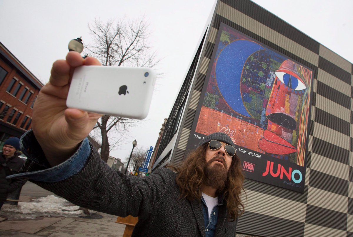 Juno Award winner Tom Wilson, (Lee Harvey Osmond, Blackie And The Rodeo Kings, Junkhouse) takes a "selfie" upon arriving for the unveiling of The Mystic Highway, an oversized mural of his artwork in Hamilton, Ont. on Tuesday, March 10, 2015.