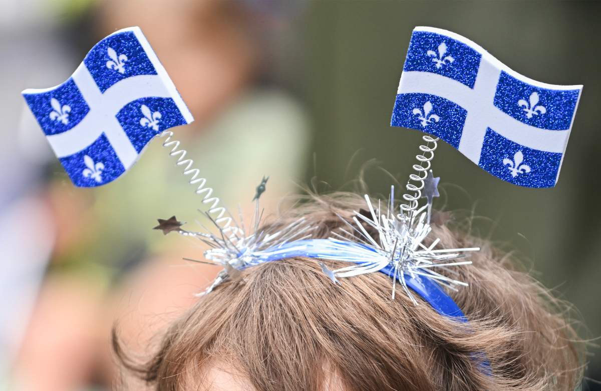 A young child wears Quebec flags on his head during Saint-Jean-Baptiste day in Montreal, Saturday, June 24, 2023.
