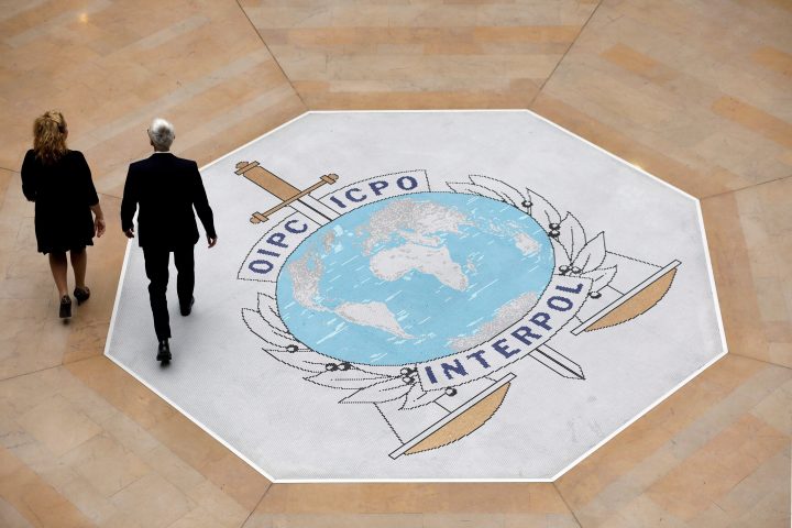 In this photo taken on Thursday, Nov.8, 2018 people walk on the Interpol logo at the international police agency headquarters in Lyon, central France.  