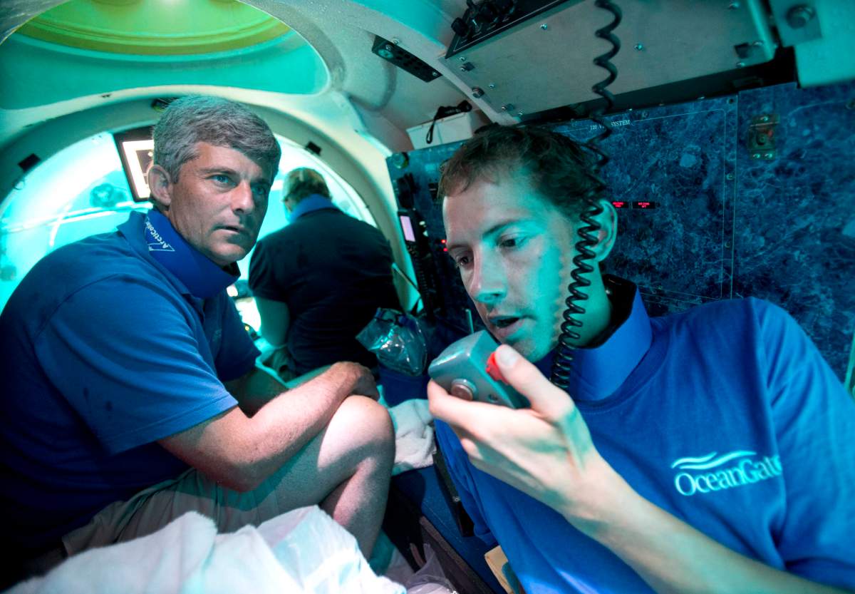 In this Friday, June 28, 2013 photo, submersible pilot Randy Holt, right, communicates with the support boat as he and Stockton Rush, left, CEO and Co-Founder of OceanGate Inc., dive in the company's submersible, "Antipodes," about three miles off the coast of Fort Lauderdale, Fla.