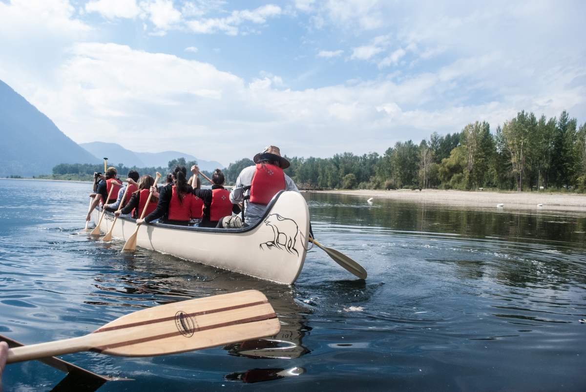 A canoe paddles down the river with people on board