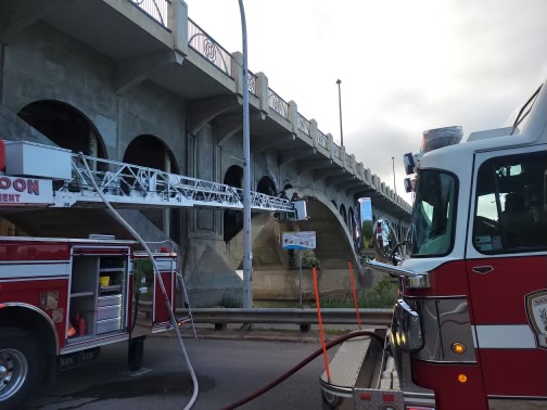 A fire is being fought by fire crews under University Bridge.