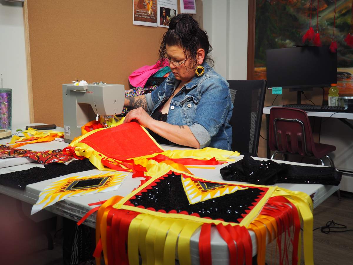 A woman sits at a sewing machine.